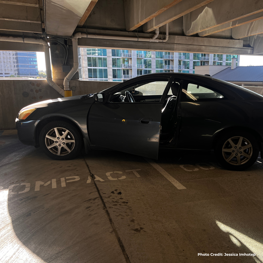 Blue car parked in a parking garage with a building in the background 3