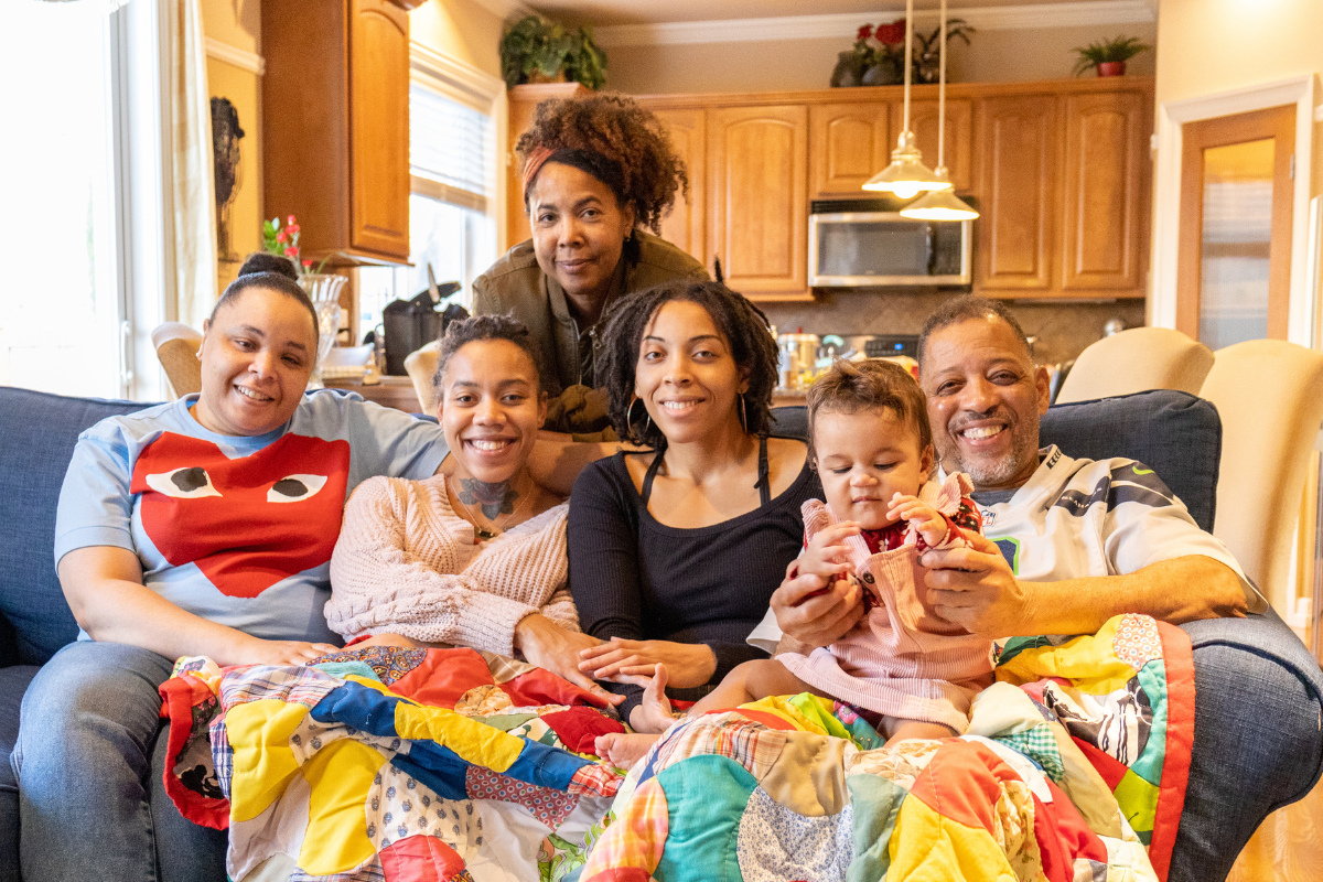 Family sitting together on a couch with a colorful quilt in a home setting