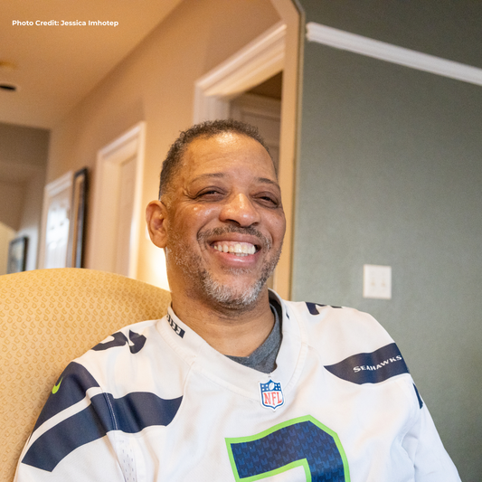 Man wearing a Seattle Seahawks jersey sitting in a chair. 1