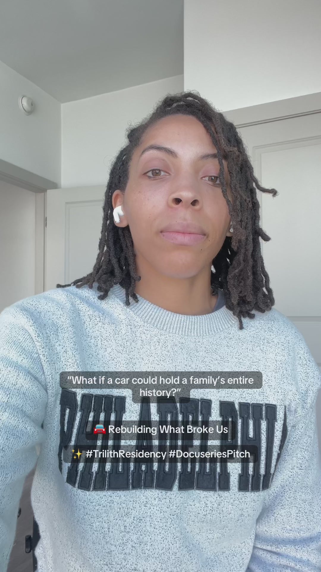 Woman wearing a Philadelphia crew neck sweater sitting in a white room talking about Rebuilding What Broke Us documentary pitch.